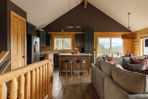 A modern kitchen with a central island, wooden cabinets, and a view to the outdoors. - Log Cabin Retreat - Hot Tub · Sauna · Game Room · Stunning Mountain Views (Pine)