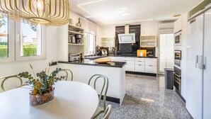 Eine moderne Küche mit einer zentralen Kochinsel, eingebauten Geräten und einem Essbereich mit Tisch und Stühlen.