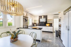 Eine moderne Küche mit einer zentralen Kochinsel, eingebauten Geräten und einem Essbereich mit Tisch und Stühlen.