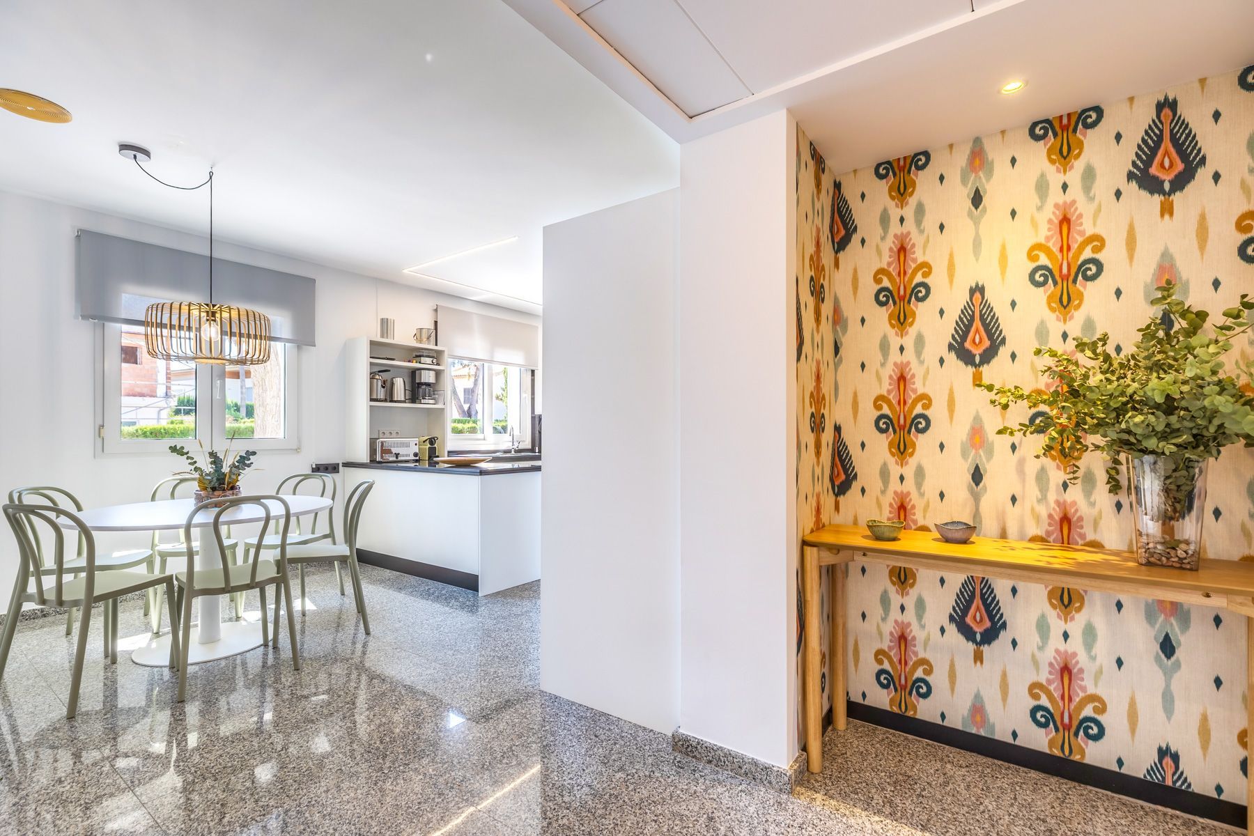 Une cuisine moderne avec des meubles blancs, un four encastré et une fenêtre.