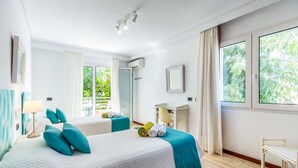 Ein Hotelzimmer mit zwei Betten, einem Schreibtisch, einem Stuhl und großen Fenstern.