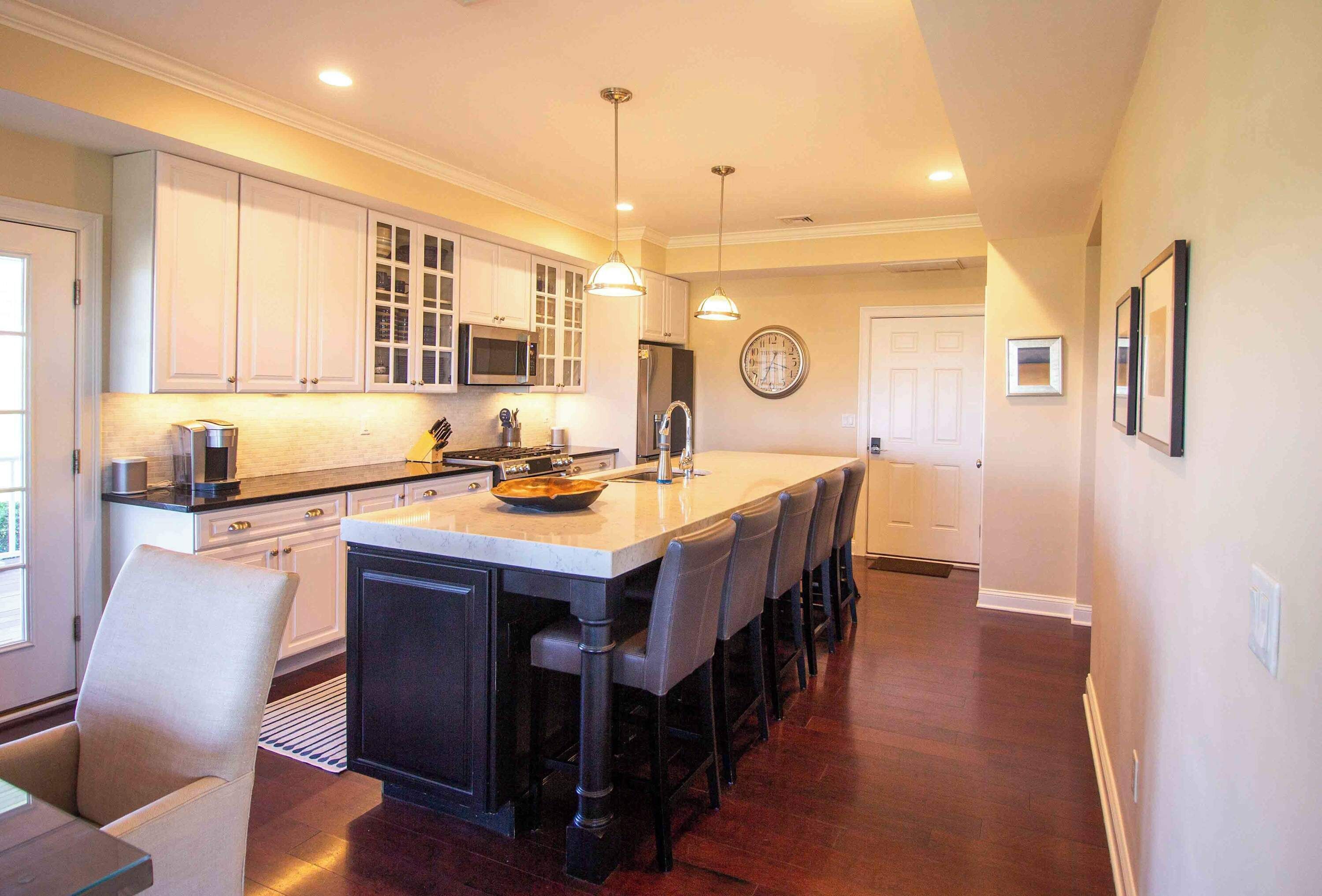A modern kitchen with white cabinetry, a central island, and a dining area with bar stools.