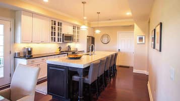 A modern kitchen with white cabinetry, a central island, and a dining area with bar stools.