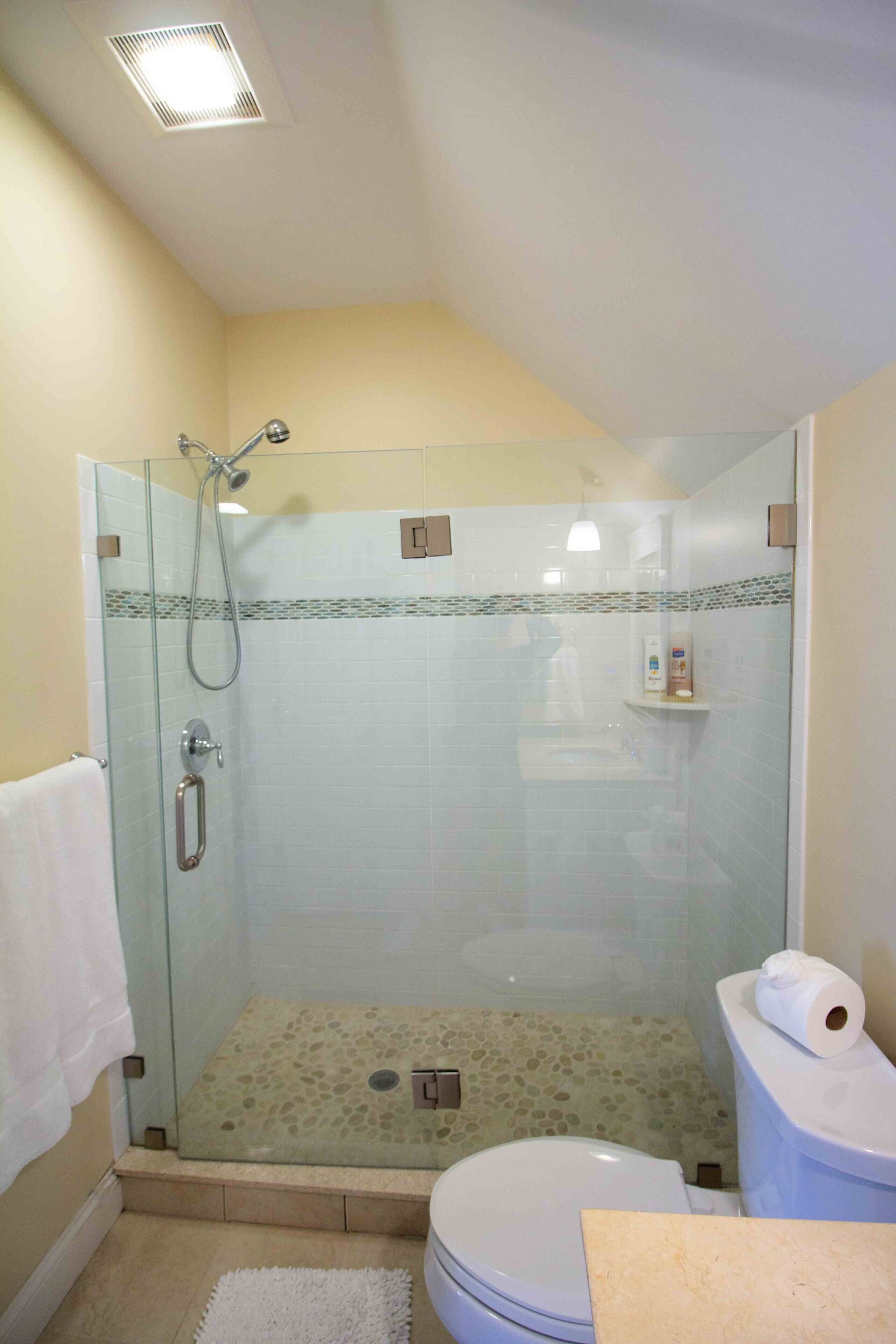 A bathroom with a glass-enclosed shower, a toilet, and a sink.