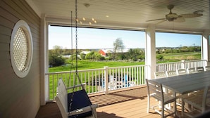 Eine überdachte Veranda mit Schaukelstuhl, Tisch und Stühlen.