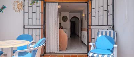 Una habitación con suelo de baldosas, una mesa con sillas, una cama y una puerta con el número indicado encima.