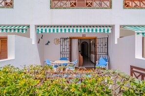 A courtyard with a table and chairs, a door with a number, and a view of the interior. - Vacation Apartment 'Victoria Court 2 51' with Shared Pool, Private Terrace and Wi-Fi (Arona)