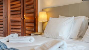 Une chambre d’hôtel avec un lit, des oreillers, une table de chevet avec une lampe et des portes en bois.