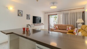 Un espacio de sala moderno con un sofá, una televisión y una mesa de comedor.