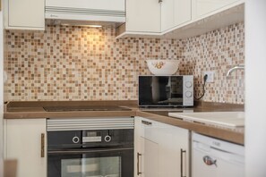 Una cocina compacta con microondas, horno y lavamanos.