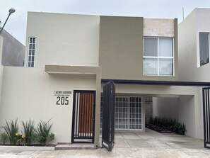 A modern building with a flat facade, a gated entrance, and a clear sign with a number.