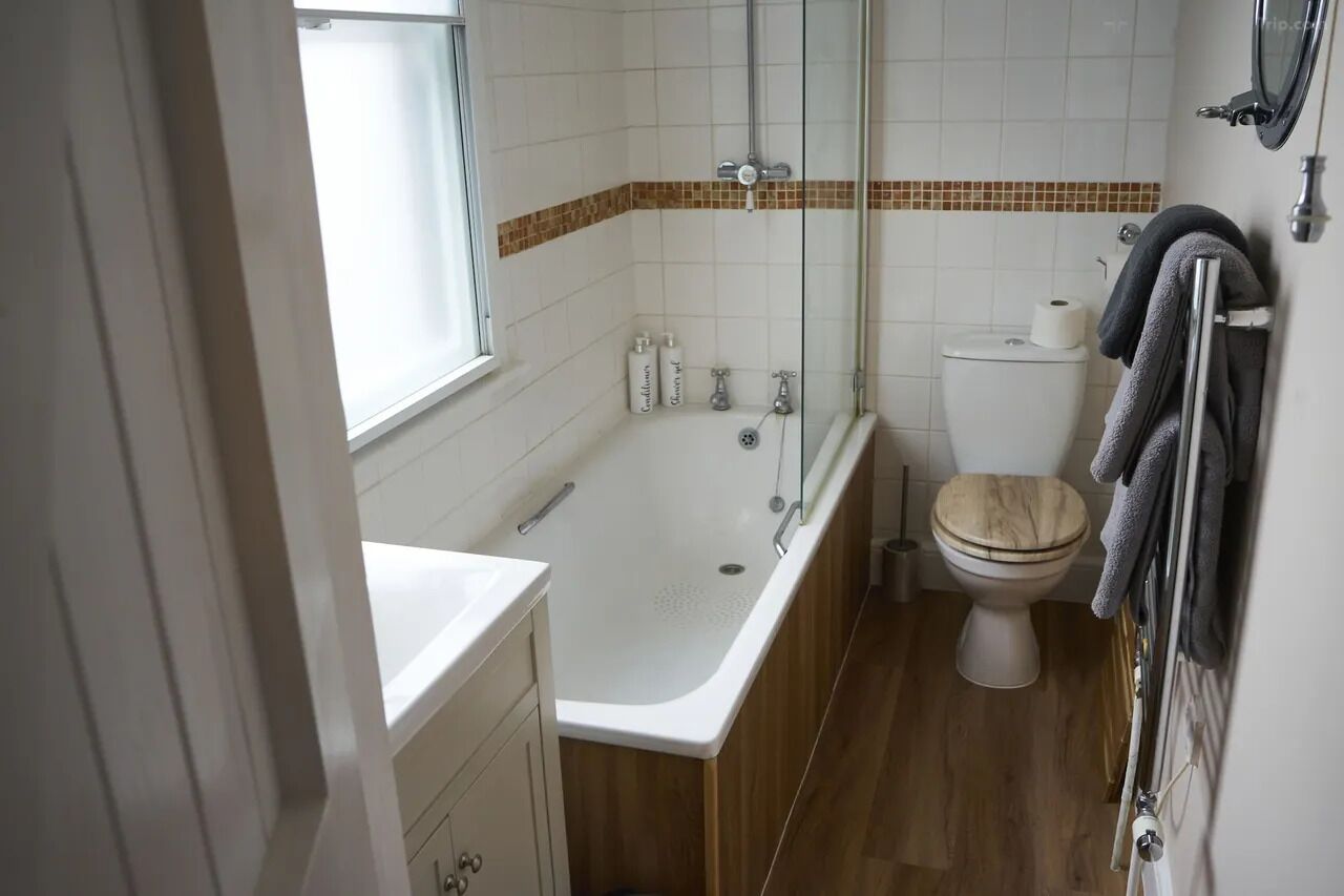Une salle de bain avec une baignoire, des toilettes et une fenêtre.