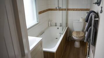 Et badeværelse med badekar, toilet og et vindue.