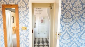 A hallway with patterned wallpaper, a checkered floor, and a sign with text. - Coachmakers Arms (Wallingford)