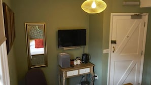 A room with a television, a small table with a coffee maker, a chair, and a door. - Coachmakers Arms (Wallingford)