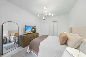 Et moderne hotelværelse med seng, fjernsyn, skab og spejl.