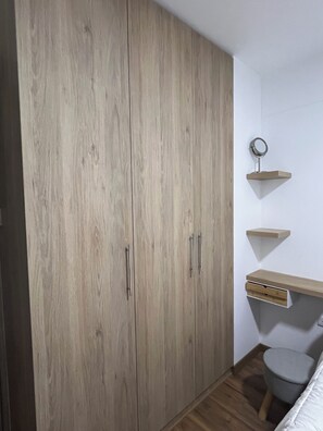 Ein Schlafzimmer mit Kleiderschrank, Nachttisch und einer kleinen Regalwand.