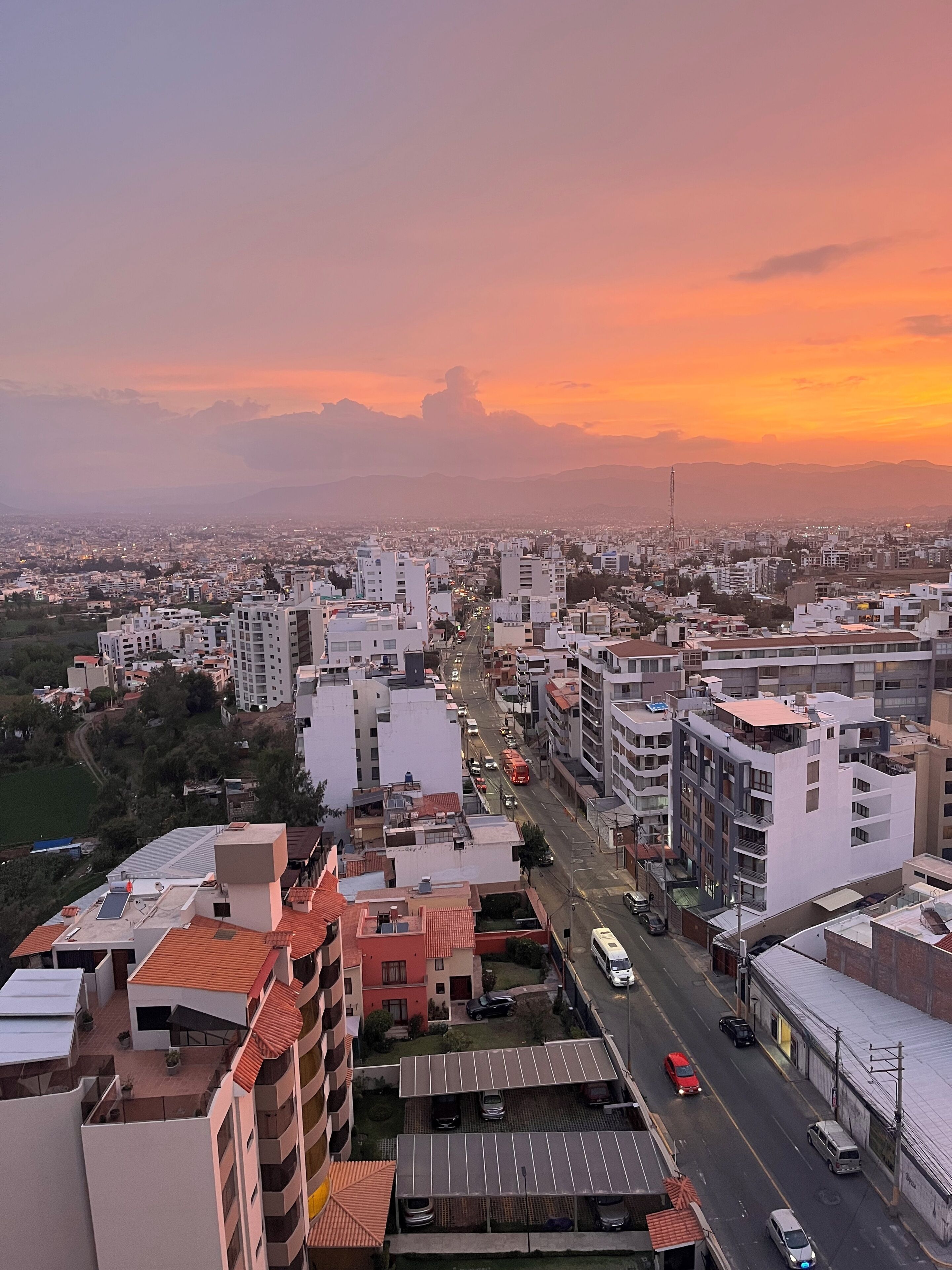 A cityscape with buildings, roads, and vehicles during sunset.