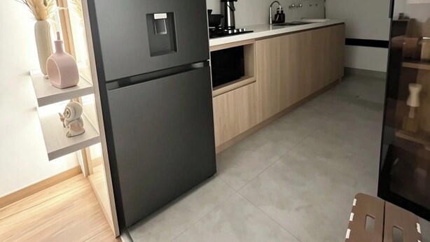 A modern kitchen with a black refrigerator, wooden cabinets, and a built-in microwave. - Rincón del Atardecer Boutique Apartment (Arequipa)