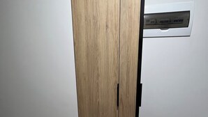 A room with a wooden wardrobe, a white wall, and a small white stool. - Rincón del Atardecer Boutique Apartment (Arequipa)