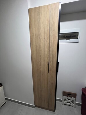 Ein Zimmer mit Holzschrank, weißer Wand und weißem Hocker.