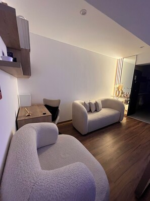 A modern living room with a sofa, a chair, a wooden side table, and a mirror. - Rincón del Atardecer Boutique Apartment (Arequipa)