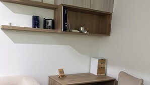 A modern room with a wooden desk, two beige chairs, and built-in shelving above the desk. - Rincón del Atardecer Boutique Apartment (Arequipa)