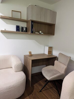 Ein modernes Zimmer mit einem Holztisch, zwei beigen Stühlen und Regalen über dem Schreibtisch.