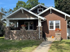 A two-story house with a stone foundation, a covered porch, and a garage.