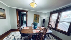 Un coin repas avec une table en bois, des chaises, un vase de fleurs et un tapis à motifs.
