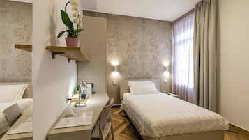 Habitación de hotel con cama, mesita de noche, lámpara y una orquídea en maceta.