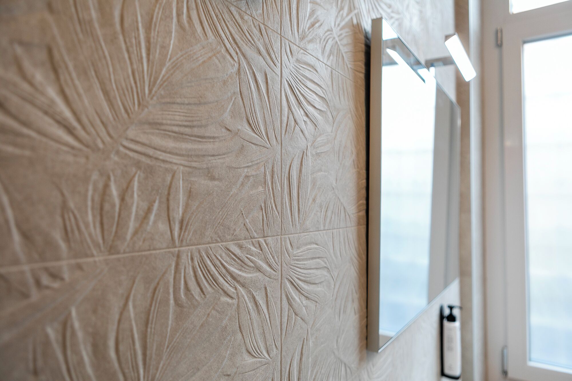 A textured wall with a leaf pattern, a window with blinds, and a door with a handle.
