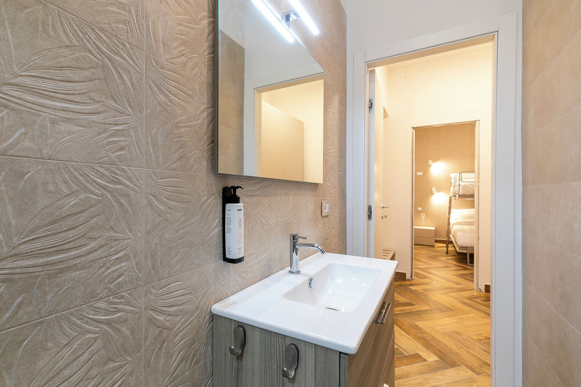 Une salle de bain avec un lavabo blanc, un miroir et un espace douche.