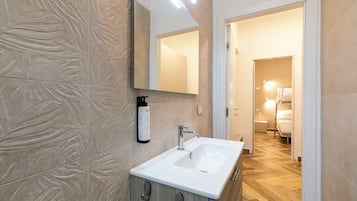 Une salle de bain avec un lavabo blanc, un miroir et un espace douche.