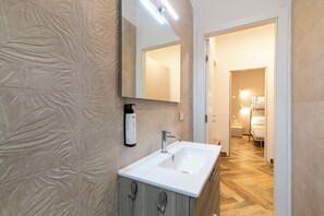 A bathroom with a white sink, a mirror, and a shower area.
