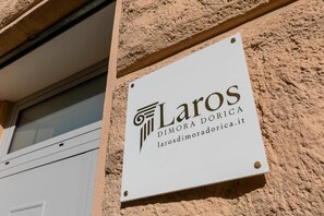Un letrero con el nombre 'Laros DIMORA DORICA' y una dirección web.