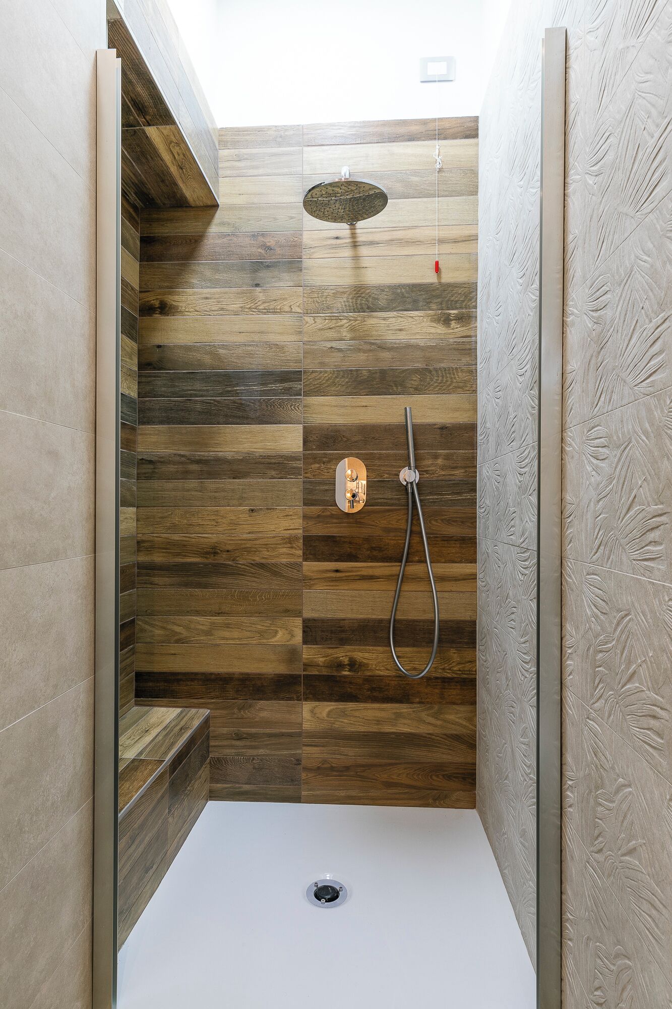 Ducha con pared de panel de madera, cabezal de ducha manual y desagüe.