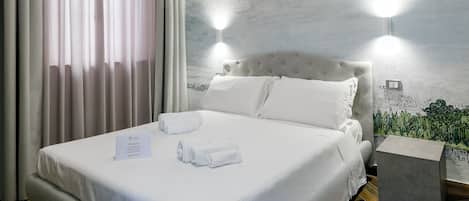 A hotel room with a neatly made bed, a bedside table, a nightstand, and a wall-mounted light fixture.