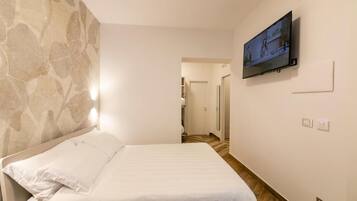 A hotel room with a bed, a television mounted on the wall, and a patterned wall.