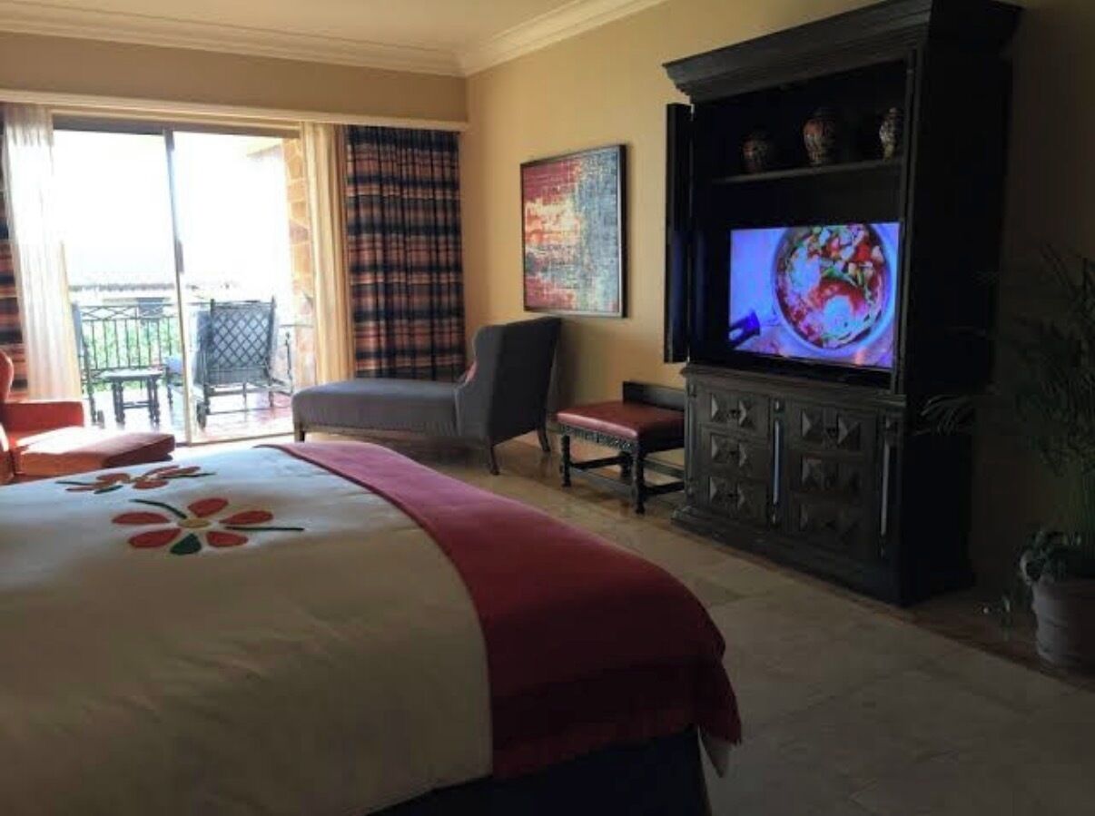 Une chambre d’hôtel avec un lit, une télévision, une chaise et un balcon.