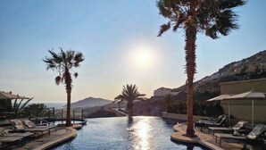 A circular infinity pool with lounge chairs and palm trees, surrounded by a poolside area with a clear view of the landscape. - Pueblo Bonito Sunset Beach Suite with 2 bedrooms/AC in pleasant Cabo San Lucas (Cabo San Lucas)