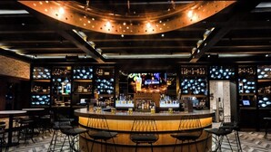 A bar area with a circular bar, multiple seating arrangements, and a television screen displaying an advertisement. - Pueblo Bonito Sunset Beach Suite with 2 bedrooms/AC in pleasant Cabo San Lucas (Cabo San Lucas)