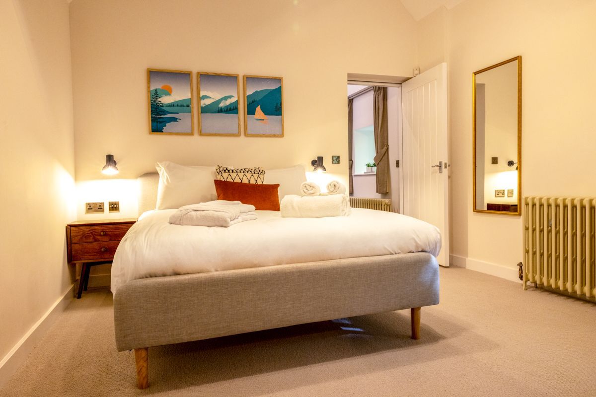 A bedroom with a bed, bedside tables, a radiator, and wall art.