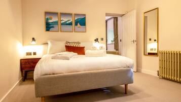 A bedroom with a bed, bedside tables, a radiator, and wall art.