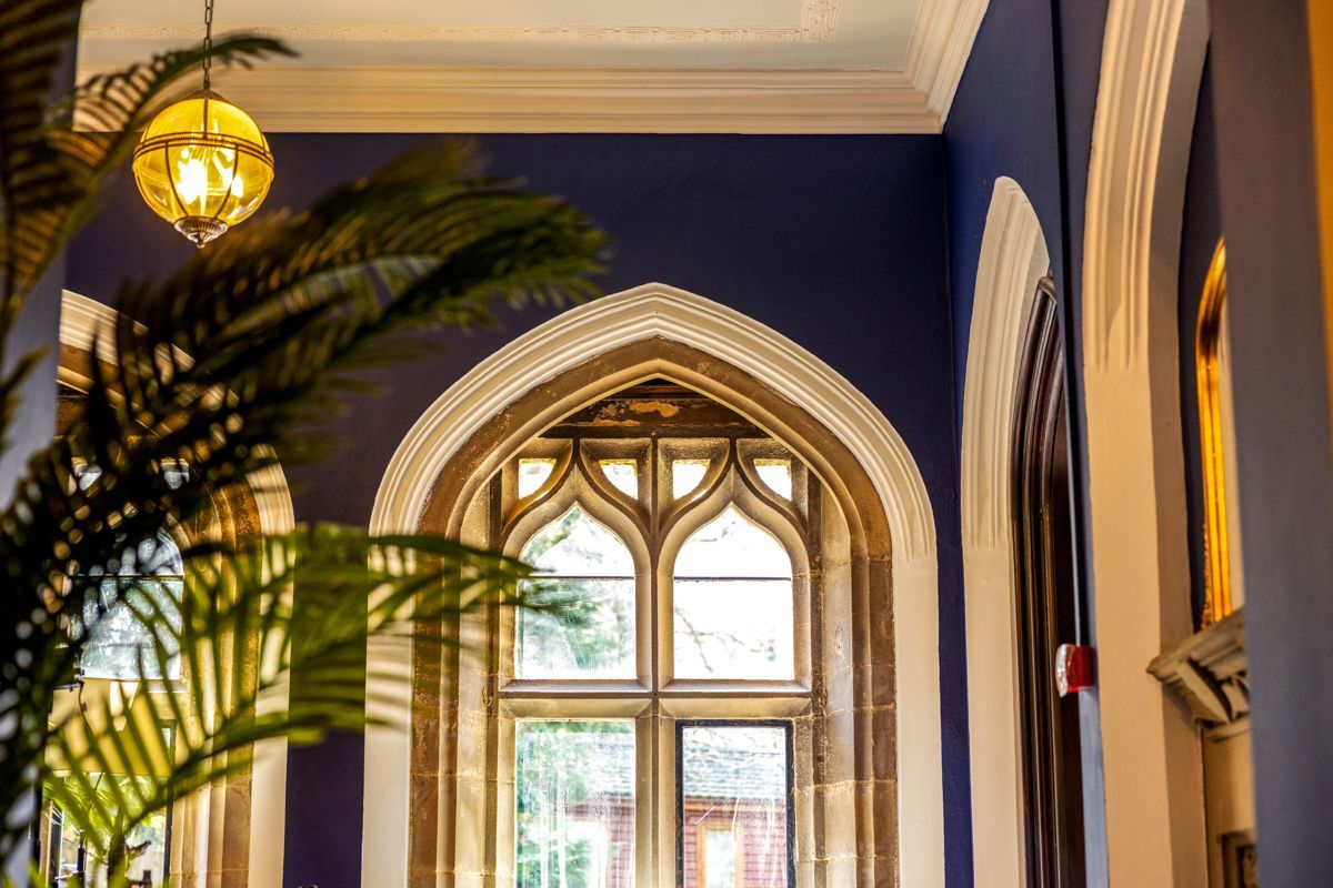 A room with a large arched window, a hanging light fixture, and a plant.