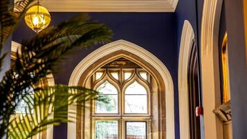 A room with a large arched window, a hanging light fixture, and a plant.