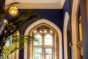 A room with a large arched window, a hanging light fixture, and a plant. - Windermere Gothic Mansion (Bowness on Windermere)