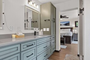 Une salle de bain moderne avec un grand miroir, un meuble-lavabo et un espace douche.