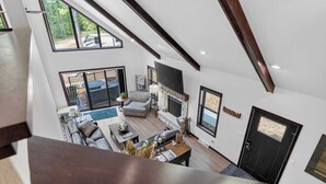 Un vaste espace de vie doté d’une cheminée, de coins salon et offrant une vue sur l’extérieur.
