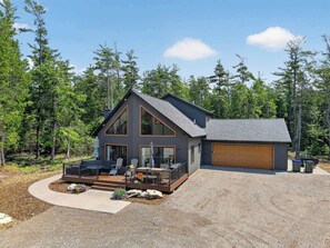 A modern two-story cabin with a deck, garage, and surrounded by dense forest. - Dog Friendly home in Baileys Harbor near Cana Island Lighthouse (Baileys Harbor)